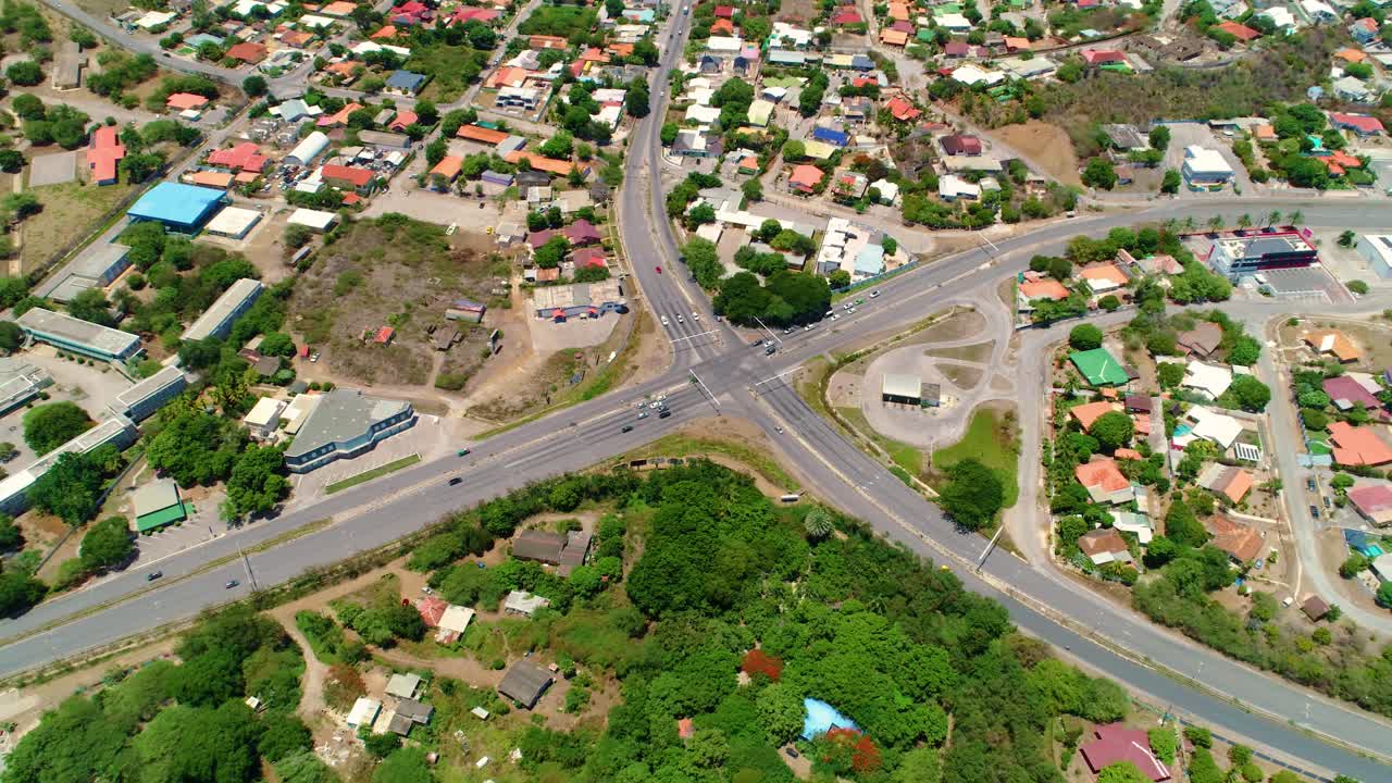 Bird's eye view pullback above curacao caribbean road highway intersection reveals urban sprawl city