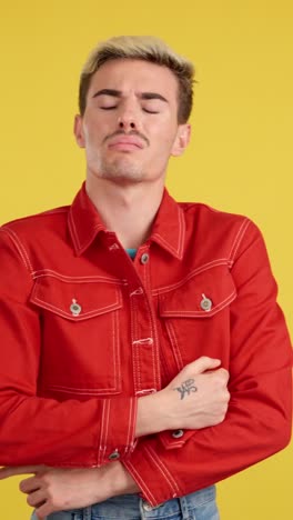 man in red jacket posing against yellow background