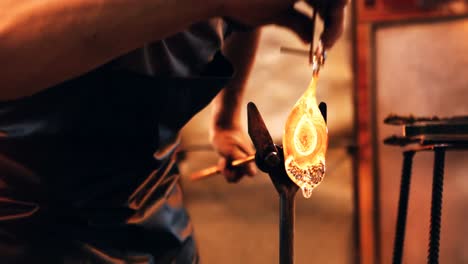 glassblower reheating a piece of glass in furnace