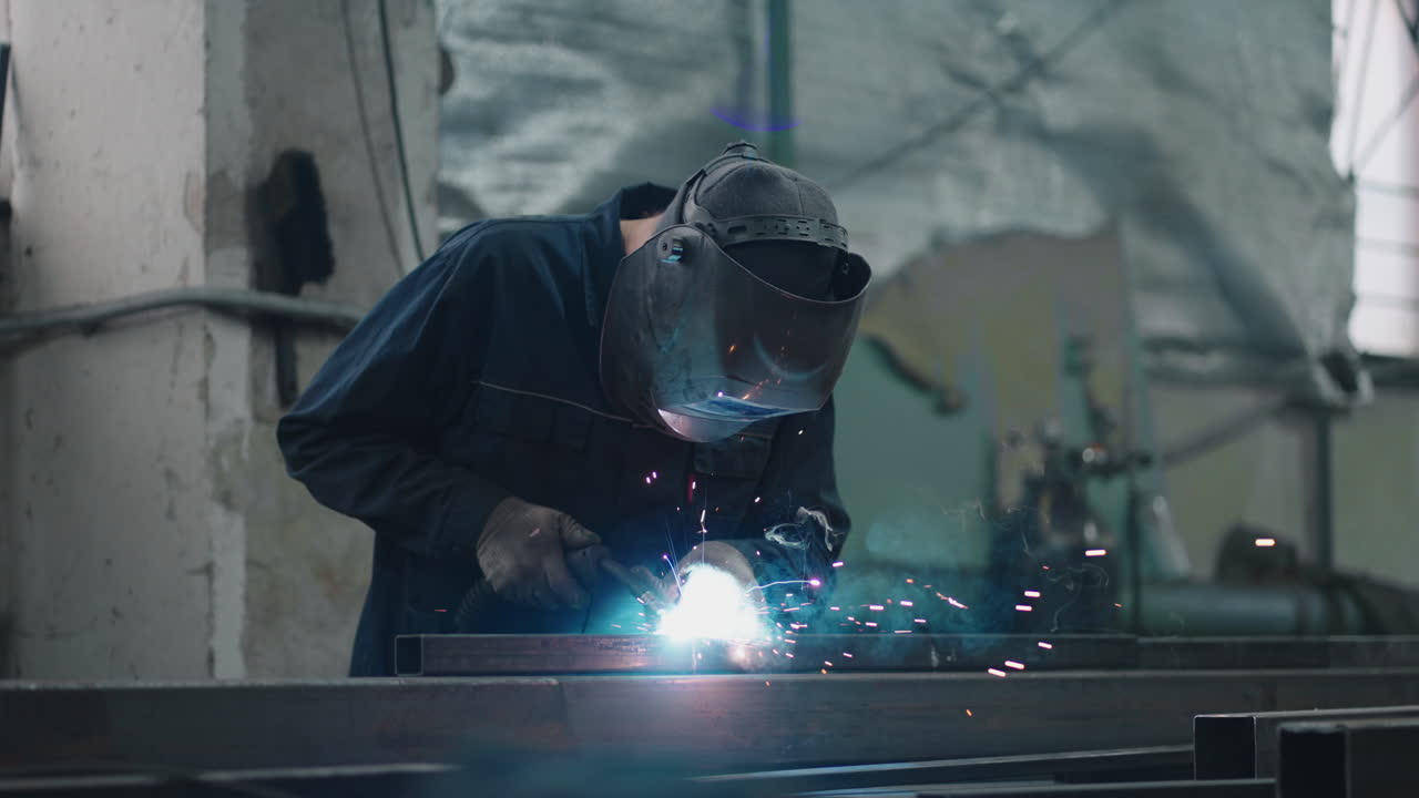 A working welder connects metal parts by gas or electric welding in slow motion. Factory and production