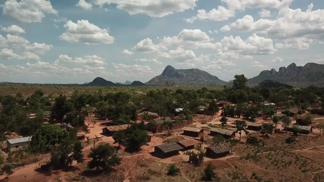 Aerial drone shot flying toward a rural village in Mozambique, with traditional houses