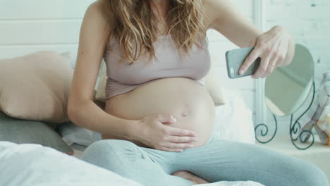 closeup pregnant woman taking photo of belly. belly mother showing thumb up