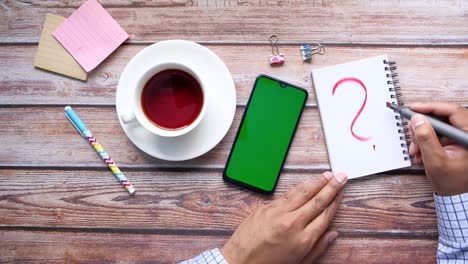 persona que escribe un signo de pregunta en un cuaderno