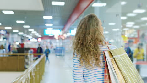 Young-Woman-With-Shopping-Bags-Over-Her-Shoulder-To-Go-Through-The-Mall-Back-View