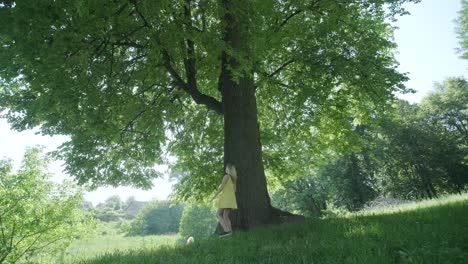 woman in yellow dress dancing by tree in summer park