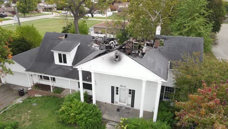 White-exterior-and-burned-down-interior-of-private-home,-aerial-ascend-view