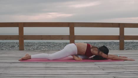 woman practicing yoga on a beach boardwalk