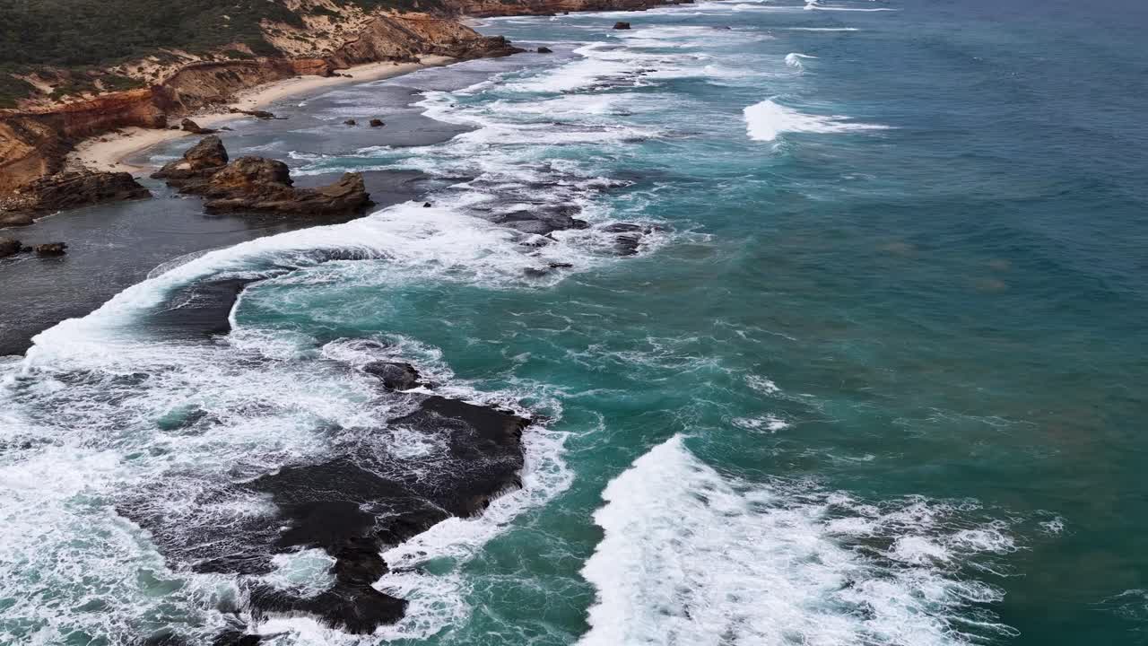 Drone captures turquoise waves breaking on rocky shoreline under natural daylight, Sorrento, Victoria, Australia