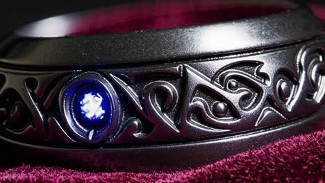 closeup of a dark, engraved ring with a blue gemstone