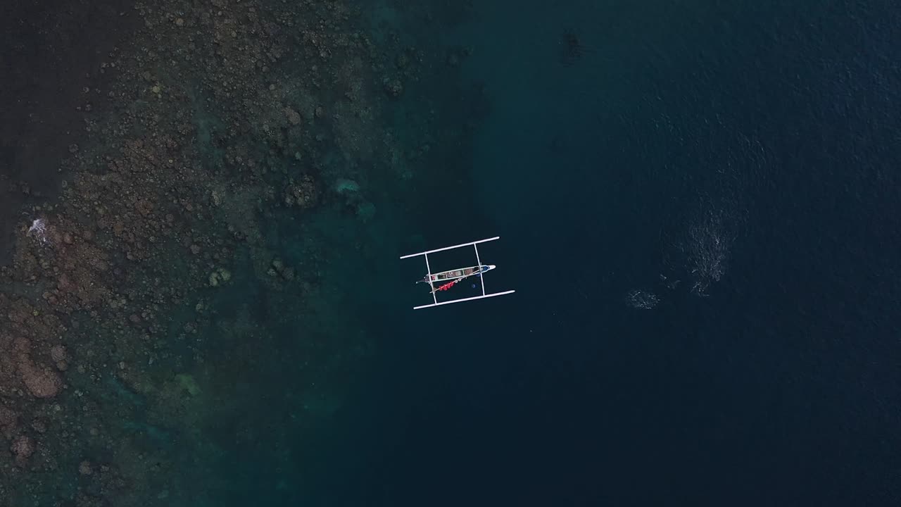 Balinese fishing boat near fish bank, Aerial overhead boom up, Bali