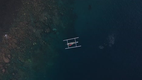 balinese fishing boat near fish bank, aerial overhead boom up, bali