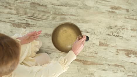 crop sound therapist playing bowl gong with rippled aqua