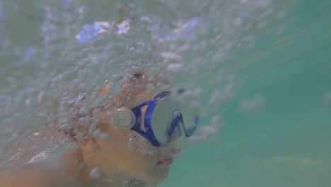 child in snorkel mask swimming underwater