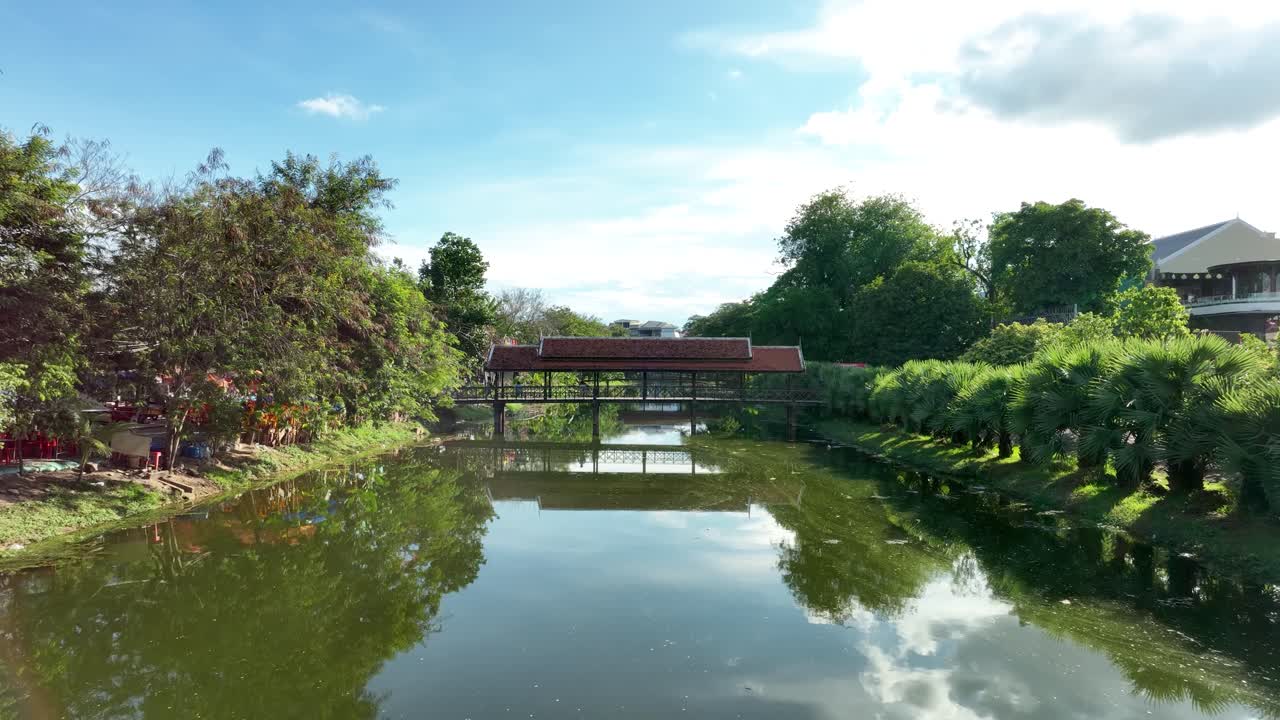 Beautiful aerial view of a bridge over the Siem Reap River in Cambodia, surrounded by lush greenery and clear blue skies