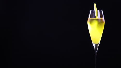 a lemon sour cocktail in a glass with a lemon slice garnish, set against a black background with bright lighting