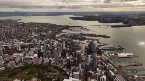 city skyline with skyscraper in downtown of auckland and famous auckland harbour bridge in background. aerial wide shot