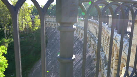 old dam holding back water from "el chorro" lake in spain, old spanish construction, interesting shot looking through iron hand railing