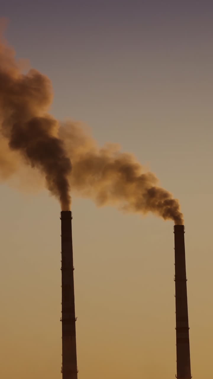 Air pollution by smoke coming out of two factory chimneys. Aerial view. Vertical video