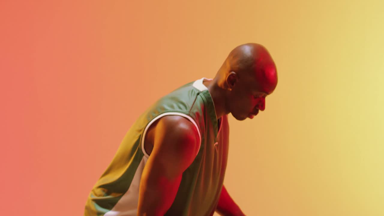 Video af afroamerikansk mandlig basketballspiller der dribler med bold på orange baggrund