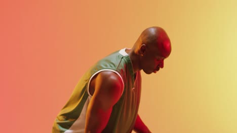 video of african american male basketball player bouncing ball on orange background