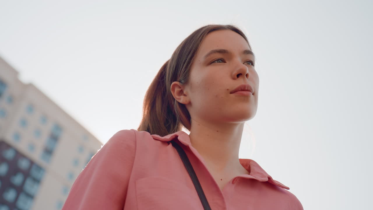 Woman Gazing Upward In City, Young Woman With Thoughtful Expression Under City Lights At Dusk, Pensive Caucasian Woman Looking Upward With Determination Amid Urban Skyline At Sunset