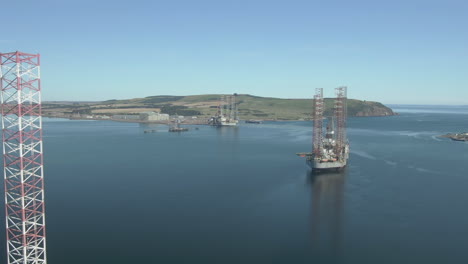 an aerial view of three oil rigs on the cromarty firth on a sunny summer's day. flying towards the rigs.