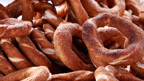 a close-up view of a pile of traditional turkish simit, with a hand reaching in to pick one