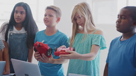 grupo de estudiantes en la clase de codificación de computadoras después de la escuela aprendiendo a programar un vehículo robot