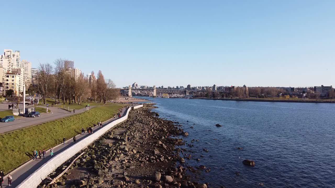 항구 na2-2 옆 주거 전용 고급 지역에서 조류가 낮고 놀랍도록 맑고 푸른 하늘에 바위가 있는 해안가 해변 지역에서 봄에 걷는 사람들 위로 공중 비행