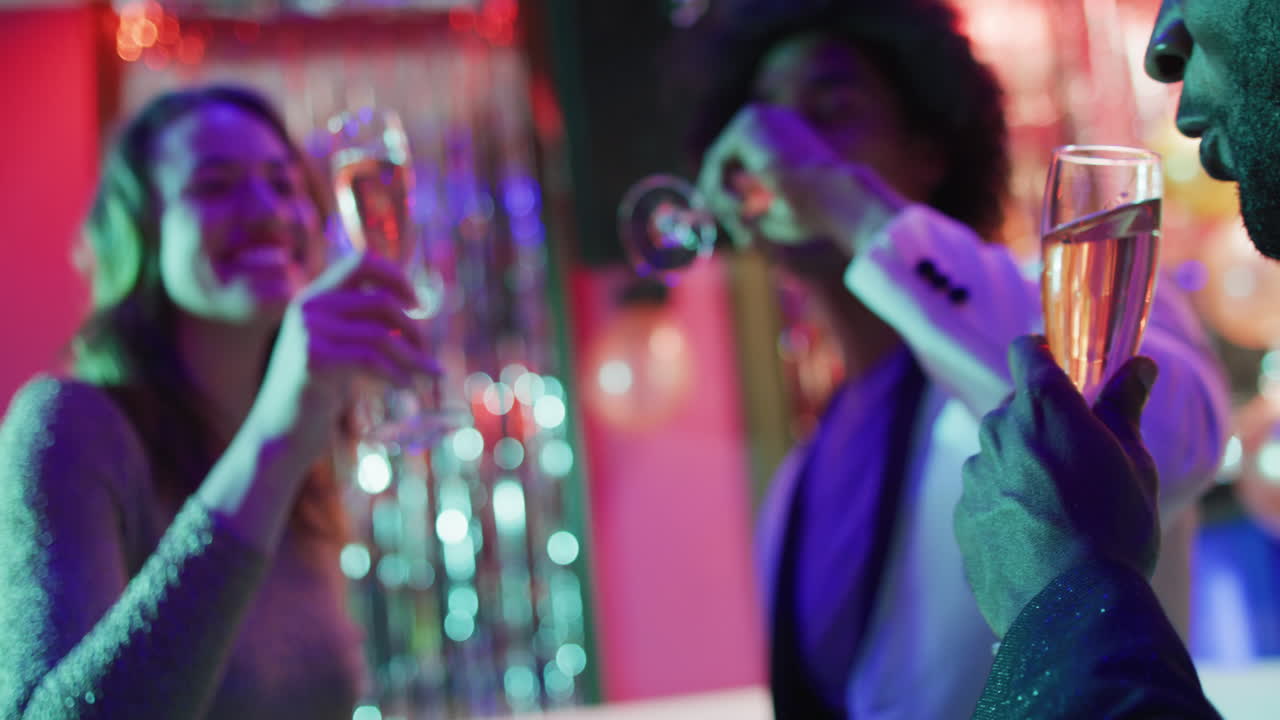 Video of a diverse group of happy friends making a toast with glasses of champagne at a nightclub