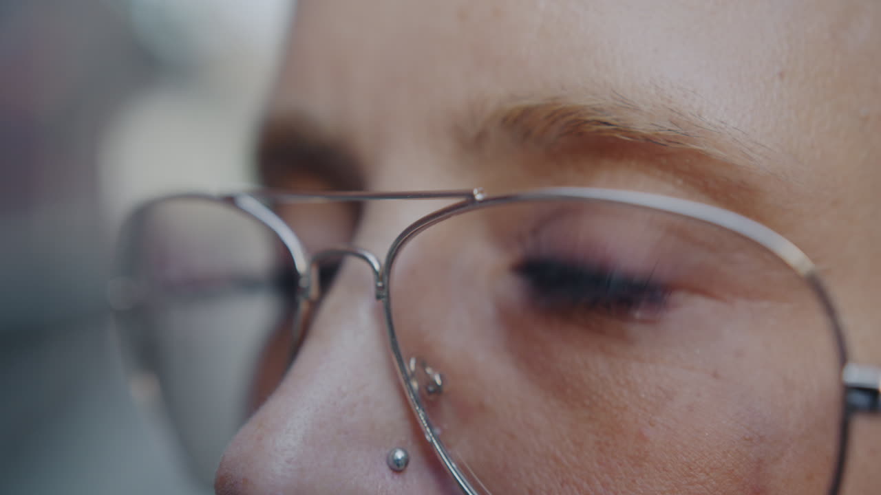 Close-up of a woman wearing glasses and a nose piercing