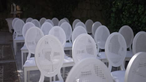 elegant white chairs arranged for an outdoor event in a garden setting