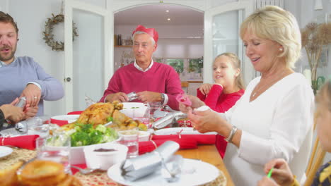 Mehrgenerationenfamilie-Zieht-Vor-Dem-Weihnachtsessen-Zu-Hause-Cracker-Und-Setzt-Papierhüte-Auf