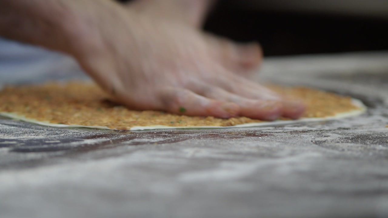 Close-up of Hands Spreading Meat Filling on Dough for Traditional Flatbread