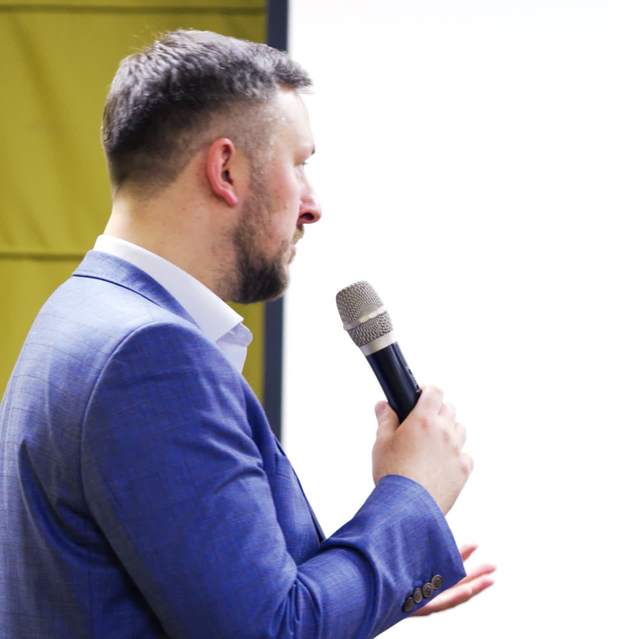 Professional confident manager speaking at symposium for the public. Businessman in suit answering the questions, giving advices, showing concept at multimedia board.