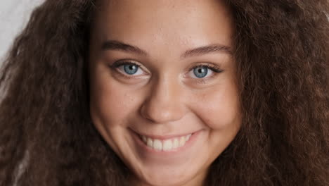 Caucasian-curly-haired-woman-smiling-to-camara.