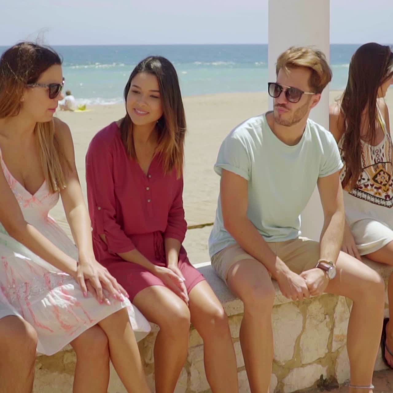 seis jóvenes estudiantes sentados charlando en una pared
