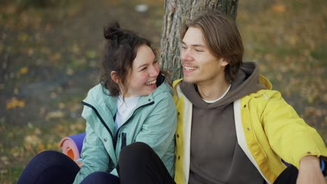 smiling couple of tourists resting together on the ground, trekking backpacker travelers concept