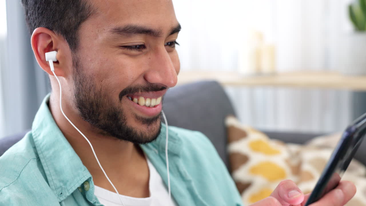 휴대폰과 헤드폰을 들고 있는 행복한 남자