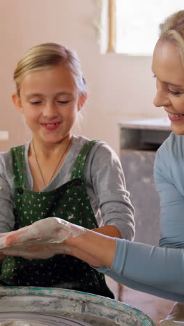 madre ayudando a sus hijas a hacer una olla