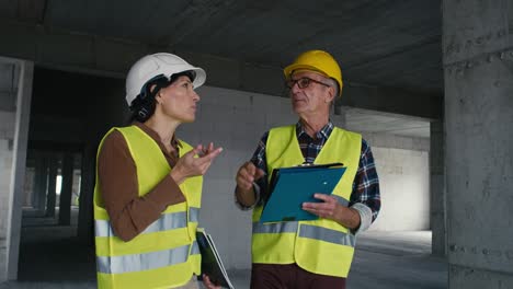 video estático de mano de ingenieros caucásicos masculinos y femeninos discutiendo y señalando el sitio de construcción.