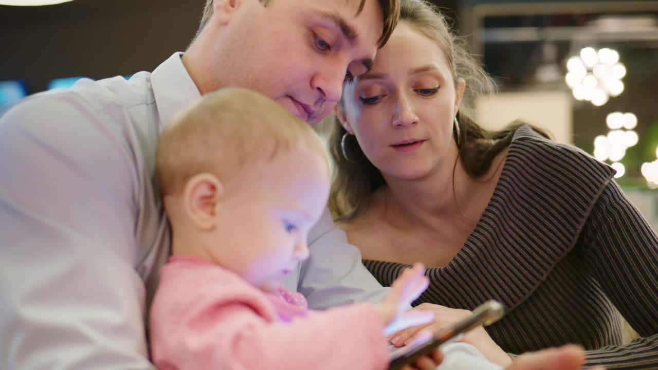 Happy Family with Baby Watching and Playing on Smartphone