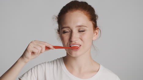 redheaded girl in front of camera on gray background.