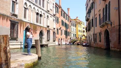 Una-Turista-Emocionada-En-El-Borde-Del-Canal-Veneciano-Sonríe-Mientras-Se-Acerca-La-Góndola