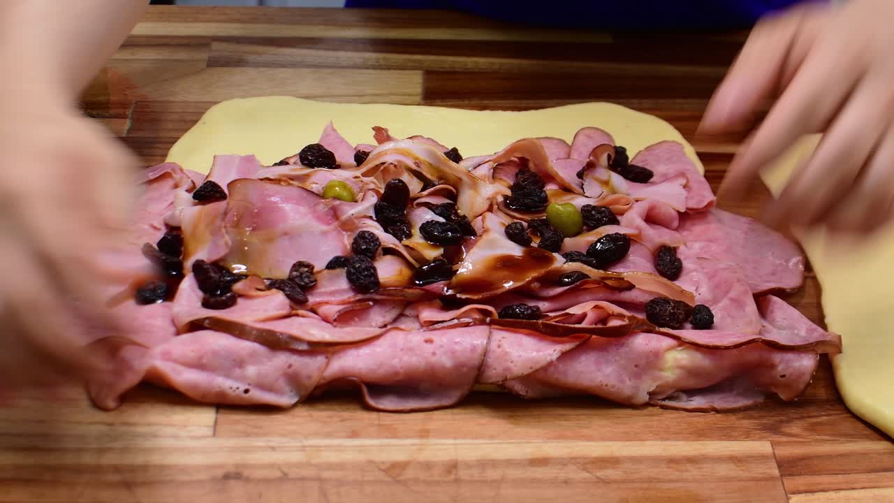 Primo piano di un fornaio che versa sciroppo scuro su impasti tradizionali di pan de jamon.