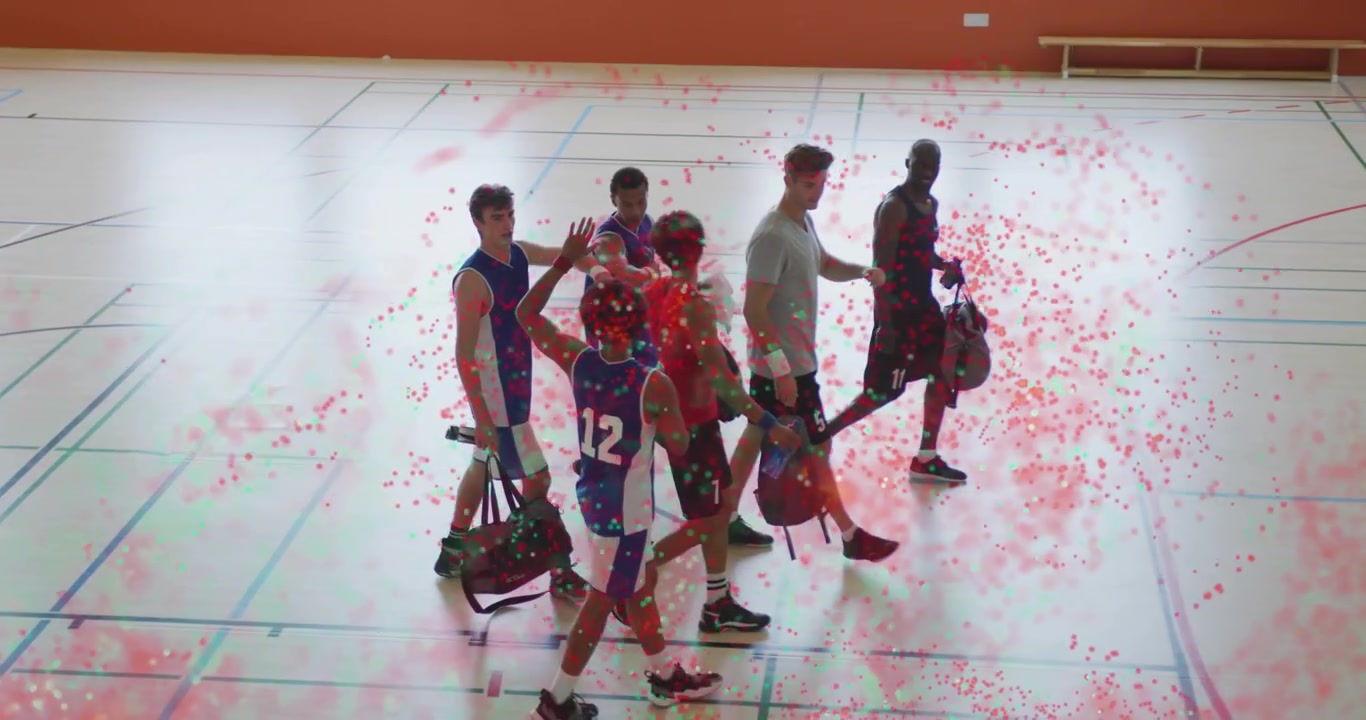 Basketbalový tým vstupuje do tělocvičny s taškami a plácá si, aby posílil týmovou soudržnost.