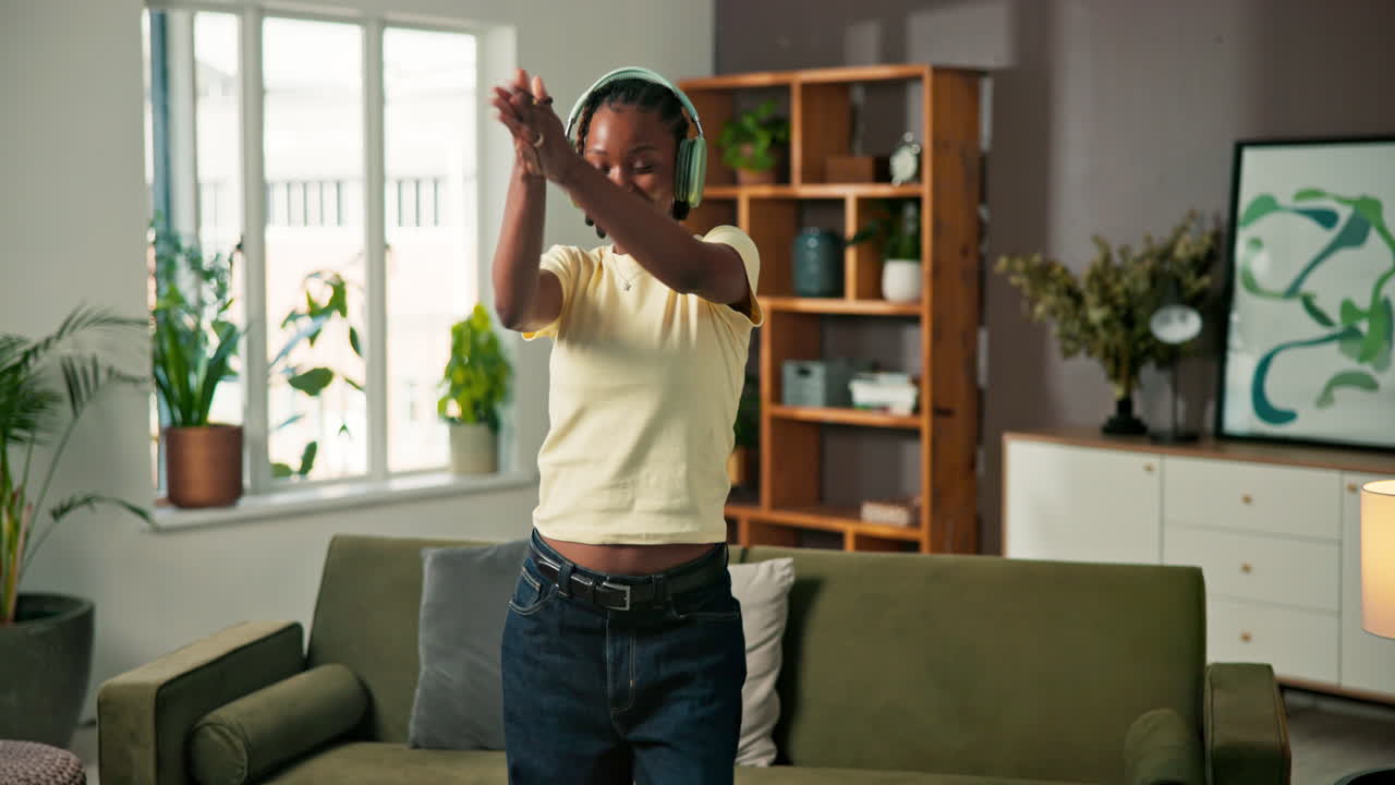 Woman dancing in her living room while listening to music with headphones