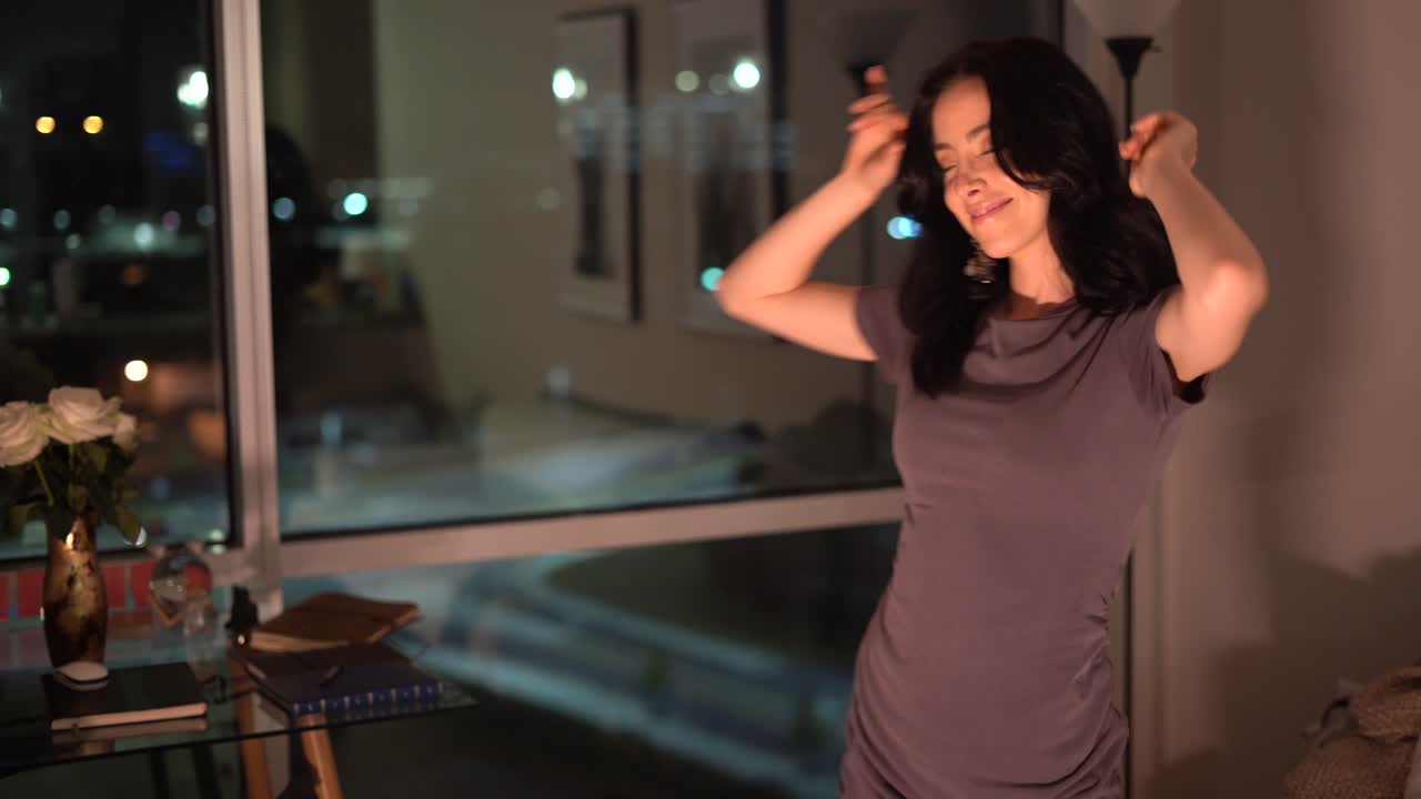 시내의 펜트하우스 아파트에서 매혹적인 젊은 여성이 춤을 추고 노래를 부릅니다.