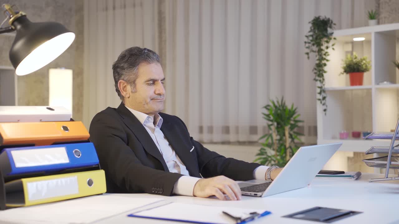 Uomo d'affari maturo stressato e in attesa, guarda il laptop al tavolo.