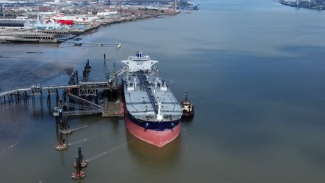 crude oil tanker ship loading at refinery harbour terminal aerial view dolly left reverse